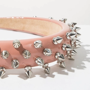 Close-up detail of pink faux leather headband featuring silver punk rock metallic spikes