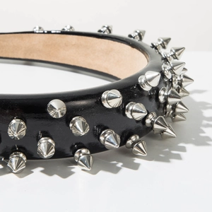 Detailed macro view of black patent leather headband with silver conical metal rivets