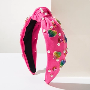 Detailed view of pink knitted headband featuring faux pearls and colorful diamond hearts