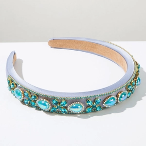 Detail of lavender satin headband with emerald green gemstones and crystal embellishments