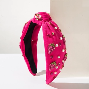 Detail of pink knitted headband with artificial pearls and rhinestone strawberry patches
