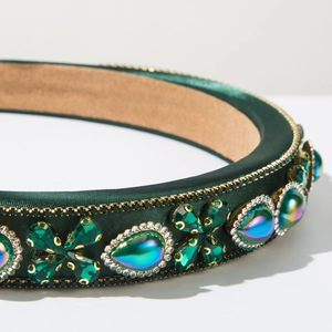 Detailed close-up of a velvet headband with green crystals and gold chain trim