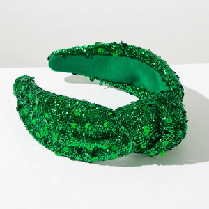 Detailed close-up of green sequined knotted headband with sparkling reflective surface