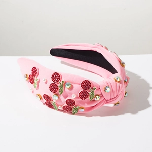 Detail of pink knotted headband with rhinestone cherry patterns and white pearls