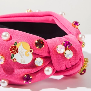 Detail of pink knotted headband with white pearls, colored rhinestones and heart rose pendant