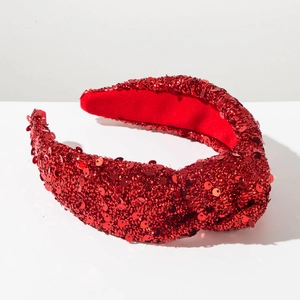 Close-up of sparkling red sequins and knotted texture on a wide Christmas headband
