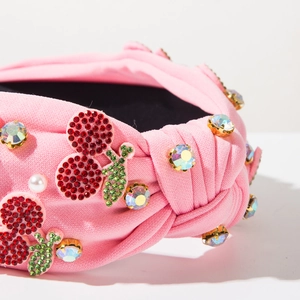 Detailed macro view of pink fabric headband with rhinestone cherries and faux pearls