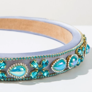 Detail of luxury baroque headband featuring turquoise gemstones and silk fabric texture