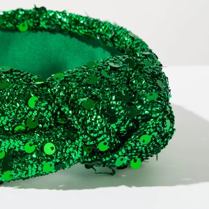 Close-up of sparkling green sequins on a padded headband showing detailed texture