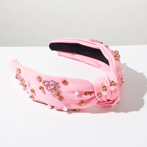 Detail of pink knotted headband with rhinestone strawberry, pearl and gold bead accents