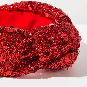 Close-up detail of red sequin headband with textured fabric and sparkling holiday finish