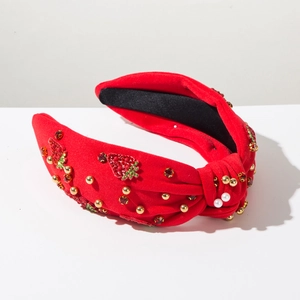 Detail of red fabric knotted headband with strawberry rhinestones, pearls and gold studs