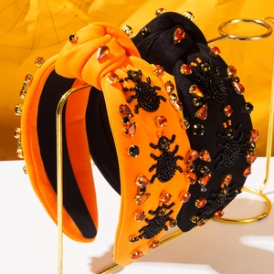 Dettaglio di ragno di perline e strass su fascia annodata arancione per Halloween