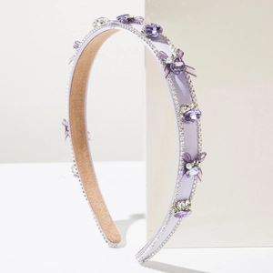 Détail d'un serre-tête violet avec cristaux et nœud en tulle sur support blanc