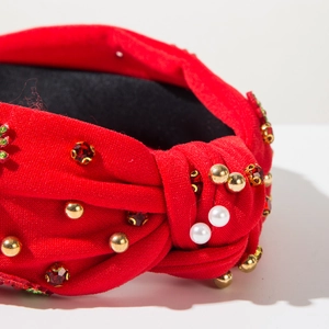 Detail of red knotted headband featuring faux pearls and red faceted crystal rhinestones
