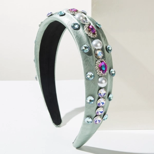 Détail d'un serre-tête large en satin vert orné de strass et de perles blanches