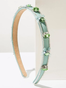 Détail d'un serre-tête vert menthe avec strass, perles et un nœud en dentelle délicat