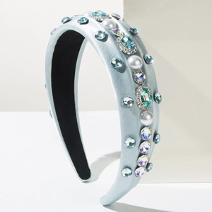 Détail d'un serre-tête en satin bleu clair avec perles blanches et strass colorés