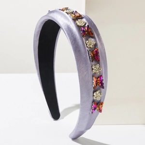 Détail macro du serre-tête en soie lavande orné de papillons et fleurs en strass colorés