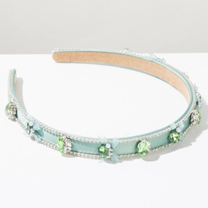Détail d'un serre-tête en satin bleu clair orné de cristaux, perles et un nœud
