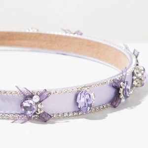 Détail du serre-tête en satin violet avec cristaux, strass, perles et nœud en dentelle
