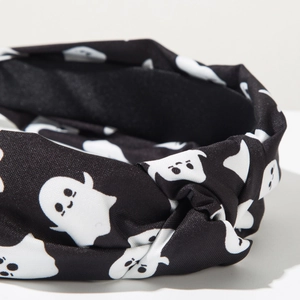 Detail of a black twisted knot headband featuring white Halloween cartoon ghost patterns