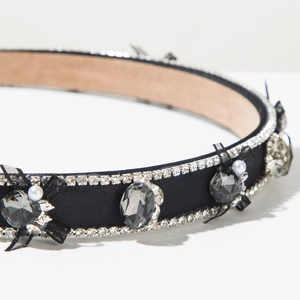 Détail d'un serre-tête en satin noir avec nœud en cristal, perles et strass brillants