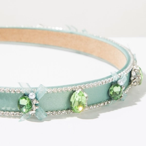 Vue macro d'un serre-tête en satin vert clair avec strass, perles et nœud en maille