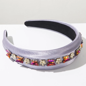 Détail du serre-tête en satin violet avec des strass brillants en forme de papillon
