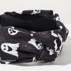 Detail of Halloween knot headband featuring white ghosts and spider webs on black fabric