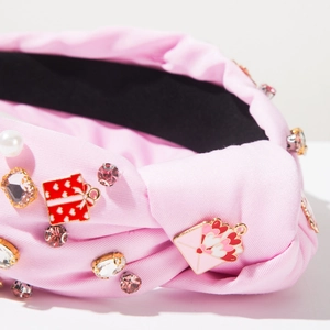 Macro shot of pink fabric headband featuring enamel heart charms and crystal rhinestones