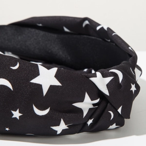 Close-up of black fabric headband featuring white moon and star patterns with a knot detail