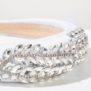 Makroaufnahme von Kristall-Strasssteinen auf weißem Samtstirnband für elegante Partys