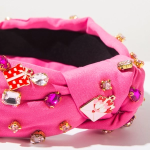 Detail of pink knotted headband featuring rhinestone bears and red enamel heart charms