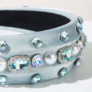 Détail du serre-tête en satin bleu clair orné de strass et de grosses perles blanches