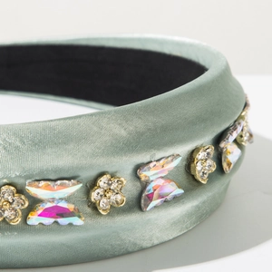 Détail macro du serre-tête en satin vert sauge avec fleurs et papillons en strass irisés