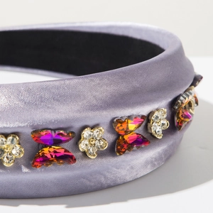 Détail macro du serre-tête en satin lilas avec fleurs en cristal et papillons irisés