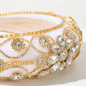Macro detail of luxury Baroque headband with gold chains and crystals on white velvet