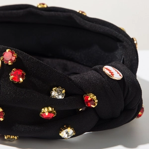 Detail of black fabric headband with rhinestones and a small baseball badge decoration