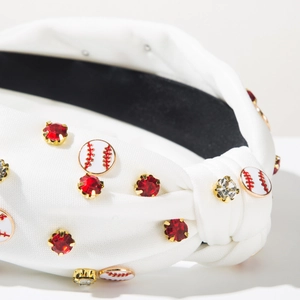 Macro detail of white fabric baseball headband with red rhinestones and enamel charms