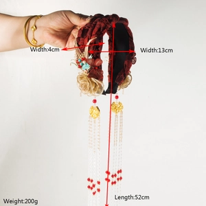 Detail of red vintage headband with gold butterfly ornaments and long pearl tassels