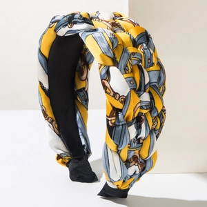 Detail of wide braided headband with yellow and blue chain pattern on white props
