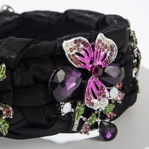 Makroaufnahme einer lila Edelsteinblüte mit Strassdetails auf einem schwarzen Stirnband