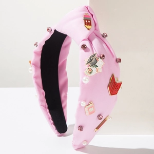 Detailed shot of pink knotted headband with pencil and book enamel charms and pearls