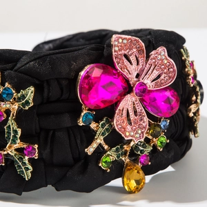 Detailansicht eines handgeflochtenen Haarreifs mit rosa Schmuck-Schmetterling und Edelsteinen