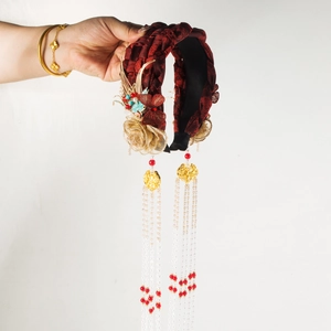 Close-up of red brocade headband with golden flowers, butterfly detail and hanging tassels