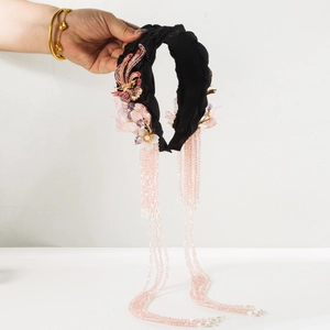 Detail of hand-woven phoenix headband with pink floral accents and long bead tassels