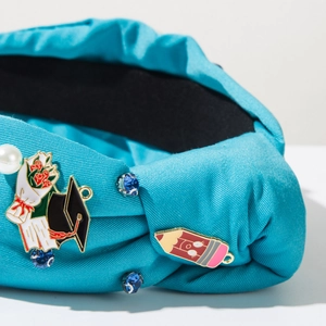 Detail of turquoise fabric headband with graduation cap, pencil badges and rhinestones