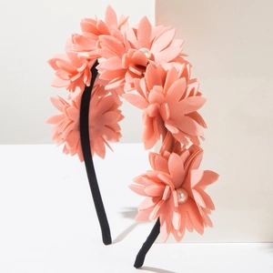 Detail of coral fabric flowers with pearls on a slim black headband for women