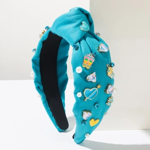 Detalle de diadema anudada azul con perlas sintéticas, colgantes de corazón y cristales